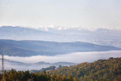Morning fog over the village and hills in Tuscany