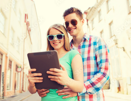 smiling couple with tablet pc in city