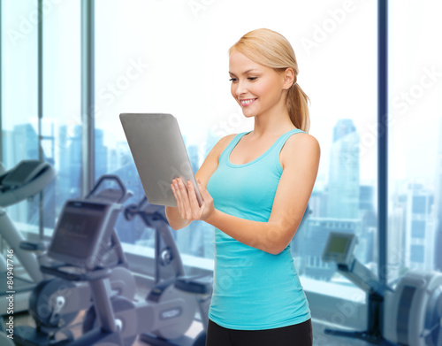 smiling sporty woman with tablet pc in gym