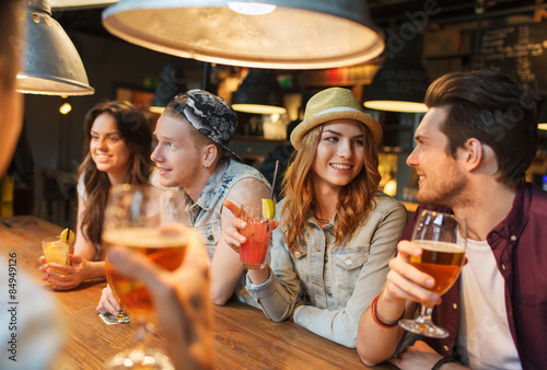 Photography happy friends with drinks talking at bar or pub