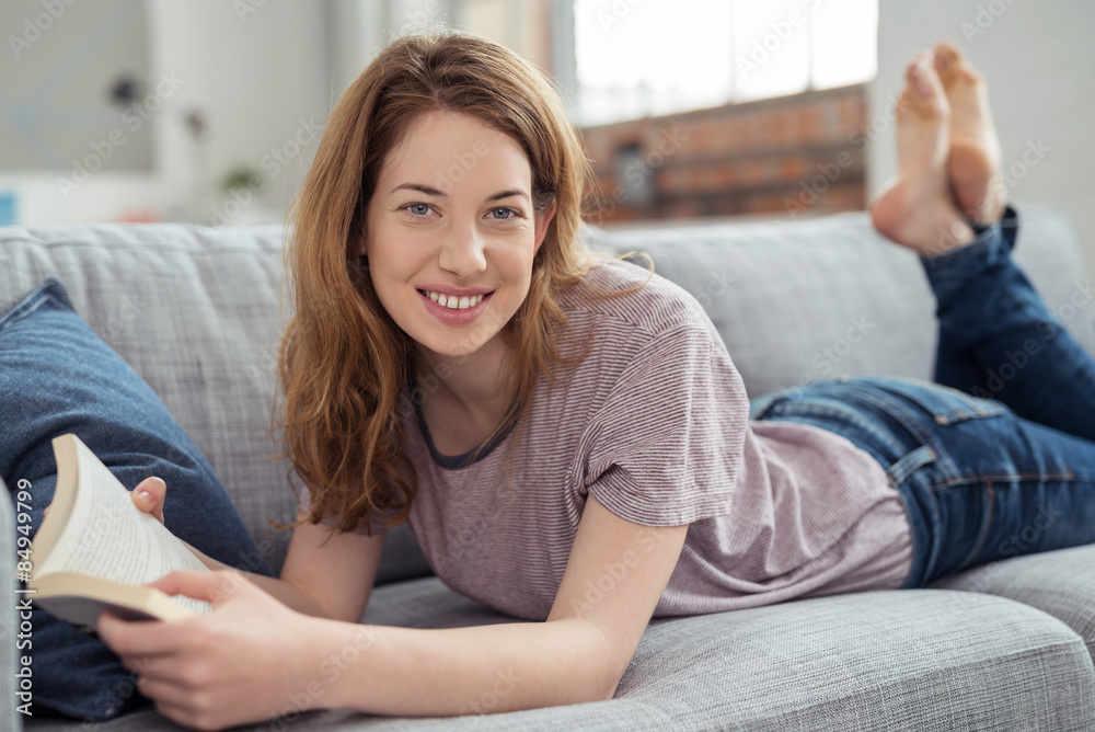 junge frau liegt auf dem sofa und entspannt mit einem buch junge frau liegt auf dem sofa und entspannt mit einem buch