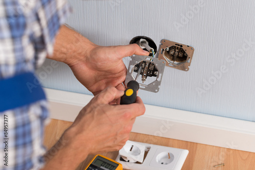 Electrician Hands Installing Wall Socket photo