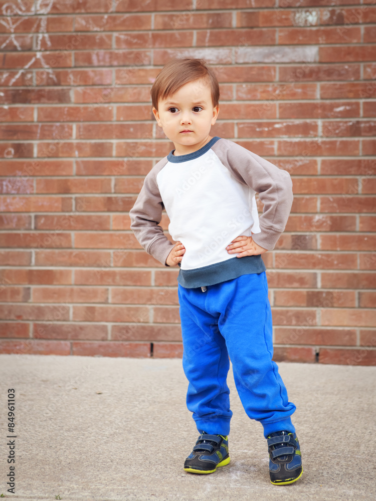 Toddler boy by brick wall laughing Toddler boy by brick wall laughing