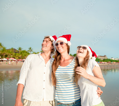Group of happy young people in christmass hats on the beach