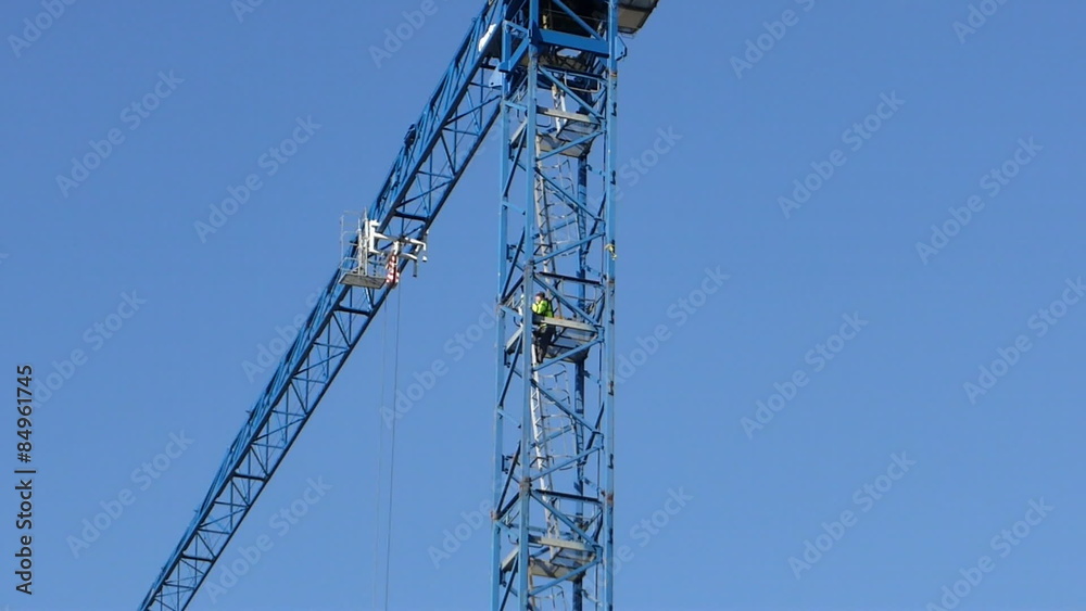 Worker climbing the ladder of working construction crane Worker climbing the ladder of working construction crane