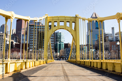 Yellow Bridge to Town - Yellow Painted Iron Bridge and Empty Road Leads Into a City of Tall Buildings