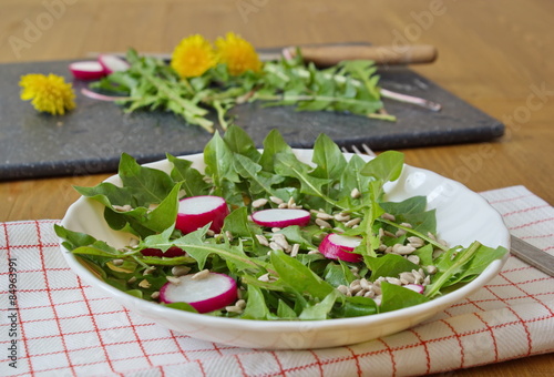 salad made by leaves of dandelion, sunflower seeds and radish