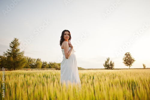 pregnant gorgeous brunette woman on the field with wheat and pop