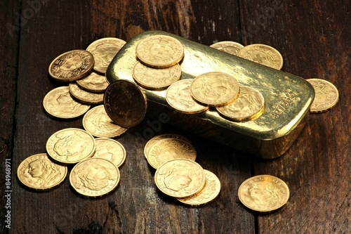 Φωτογραφία schweizer Goldvreneli mit Goldbarren auf rustikalem Holzhintergrund
