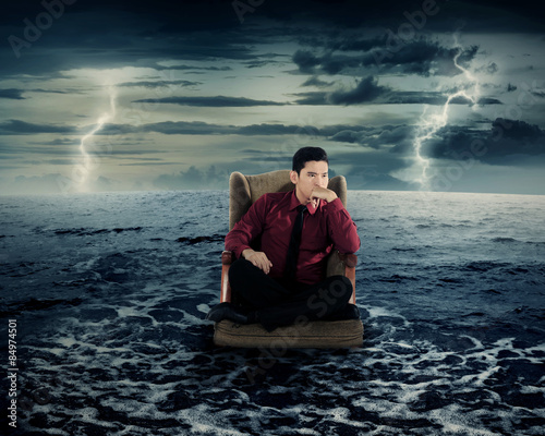Business man sitting on armchair in the ocean