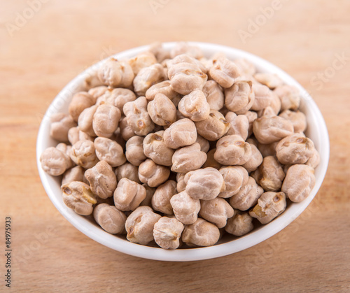 Chickpeas in a white bowl on wooden board