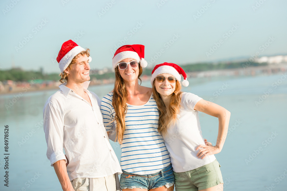 Group of happy young people in christmass hats on the beach Group of happy young people in christmass hats on the beach