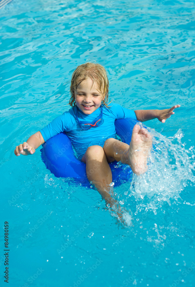 Smiling little girl in swimming goggles relaxing in the swimming pool