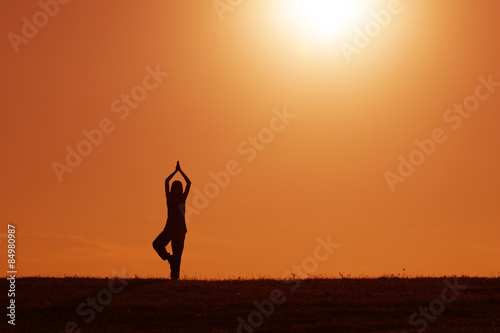 Silhouette of woman meditating in the sunset