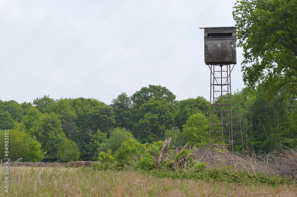 Wooden hunting hut on high poles overlooking field