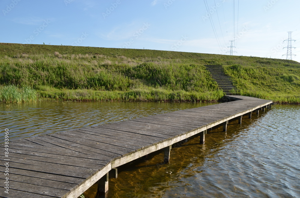 Wooden bridge to dike over lake in Antwerp polder