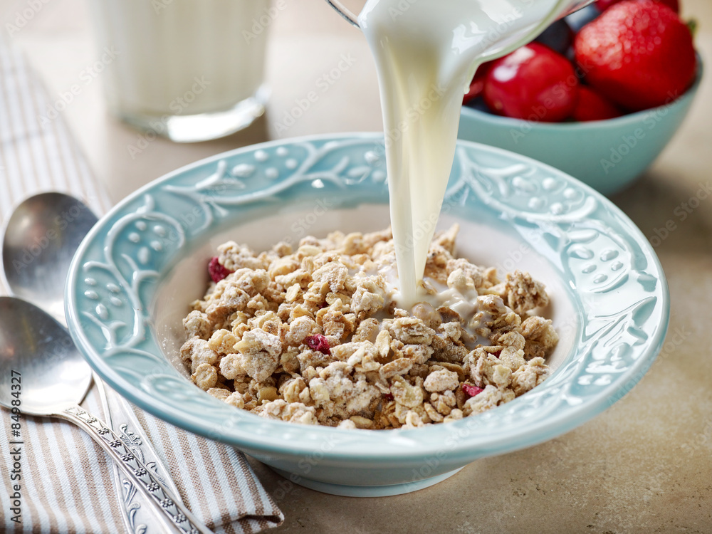pouring milk in a plate of granola pouring milk in a plate of granola