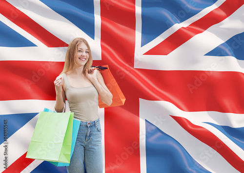 A happy young woman with the colourful shopping bags from the fancy shops. Great Britain flag background.