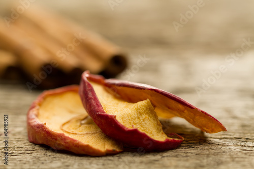 dried apples with cinnamon sticks on old wooden background. Closeup.