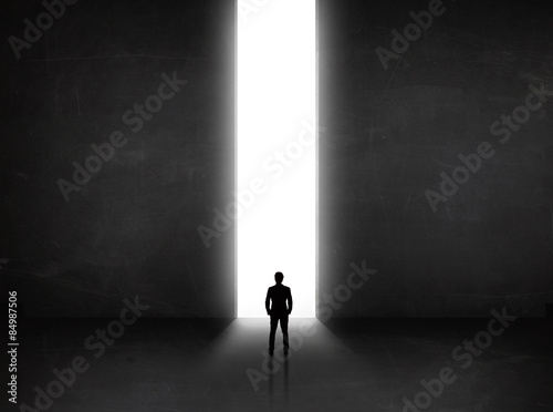 Business person looking at wall with light tunnel opening