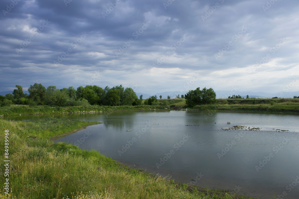 Summer landscape with lake and storm clouds