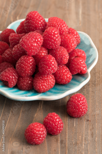 Ripe sweet raspberries on a plate on table close-up