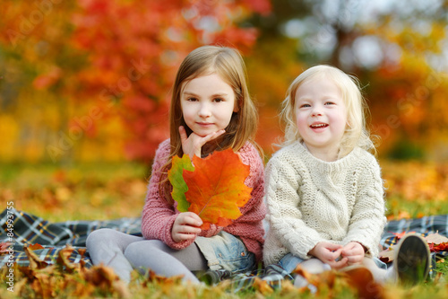 Two sisters having fun together in autumn park