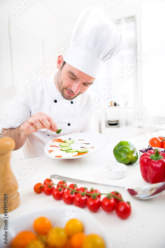 Young attractive professional chef cooking in his kitchen