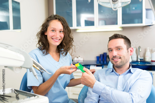 Young attractive dentist taking health insurance card of patient