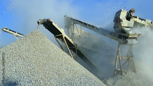 heavy machinery of gravel production in quarry. Stones breaking factory with pit and moving conveyor belt loading crushed stones. Burma, Myanmar