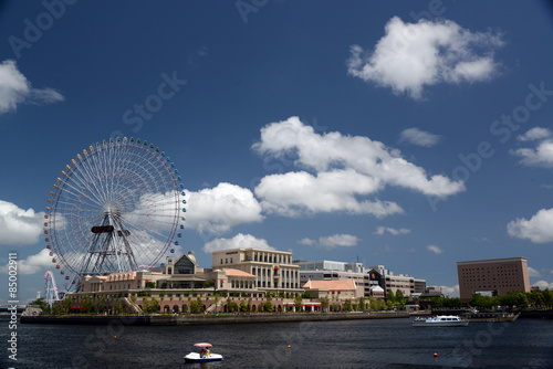 初夏の横浜初夏のみなとみらい21地区の公園、海の向こうに見える観覧車と商業施設。