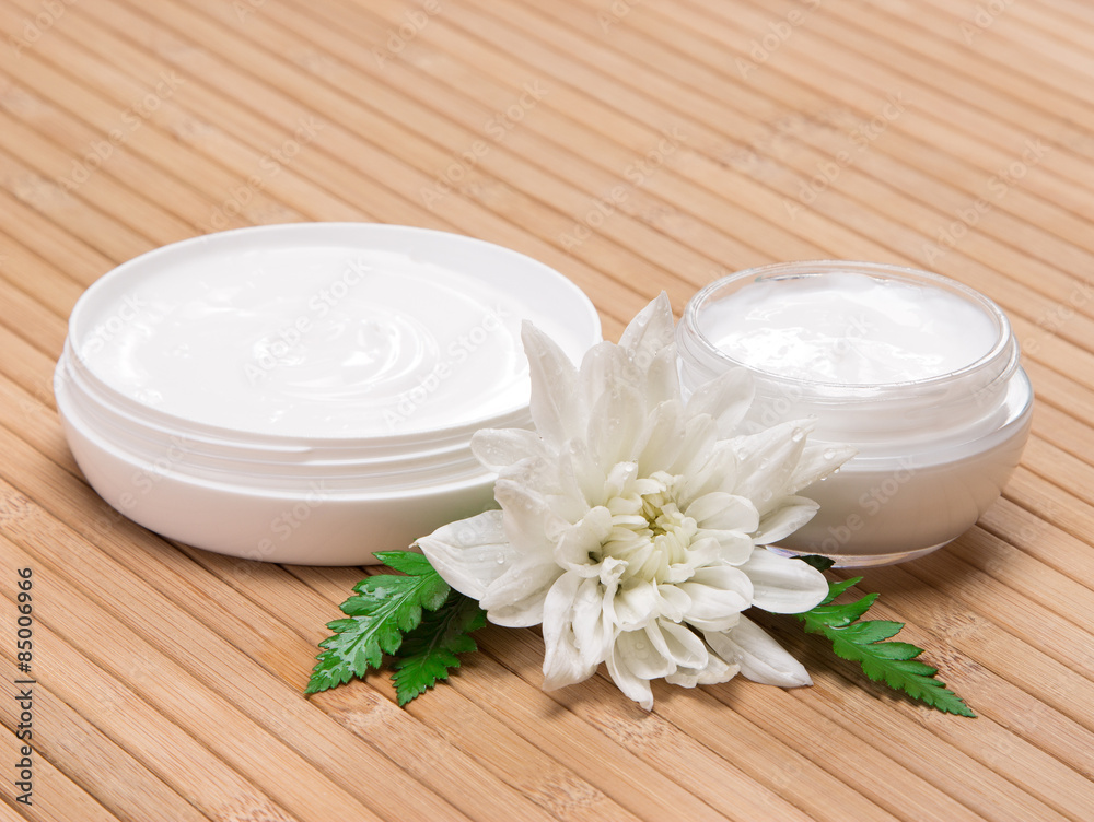 Open jars of cream with white flower and fern leaves Open jars of cream with white flower and fern leaves