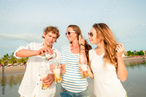 Group of happy young people drinking beer on the beach