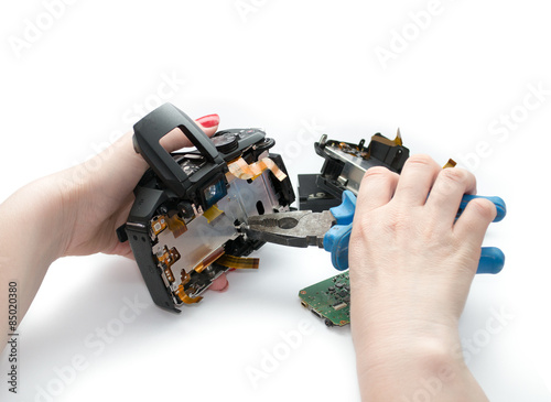Woman disassembling photo camera by pliers.