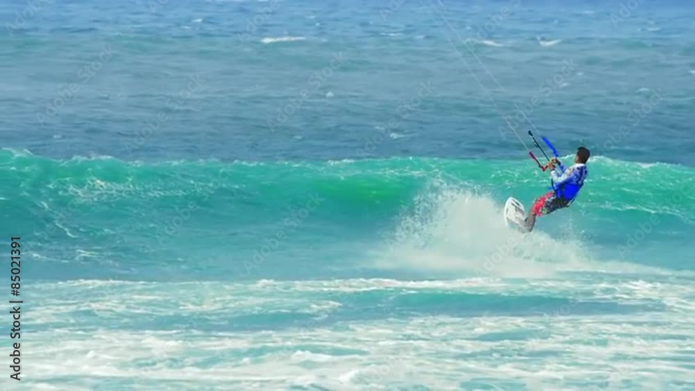 Male kite surfer jumps on wave and flies in air after making acrobatic trick