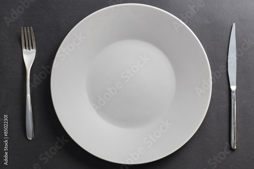 Grey dish on a black background with fork and knife