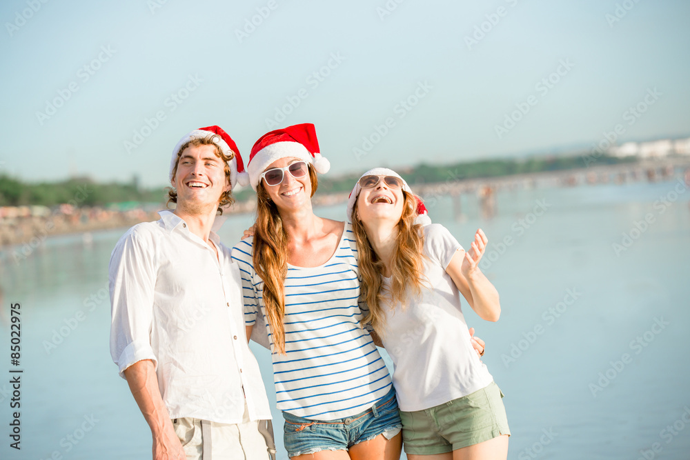 Obraz premium Group of happy young people in christmass hats on the beach