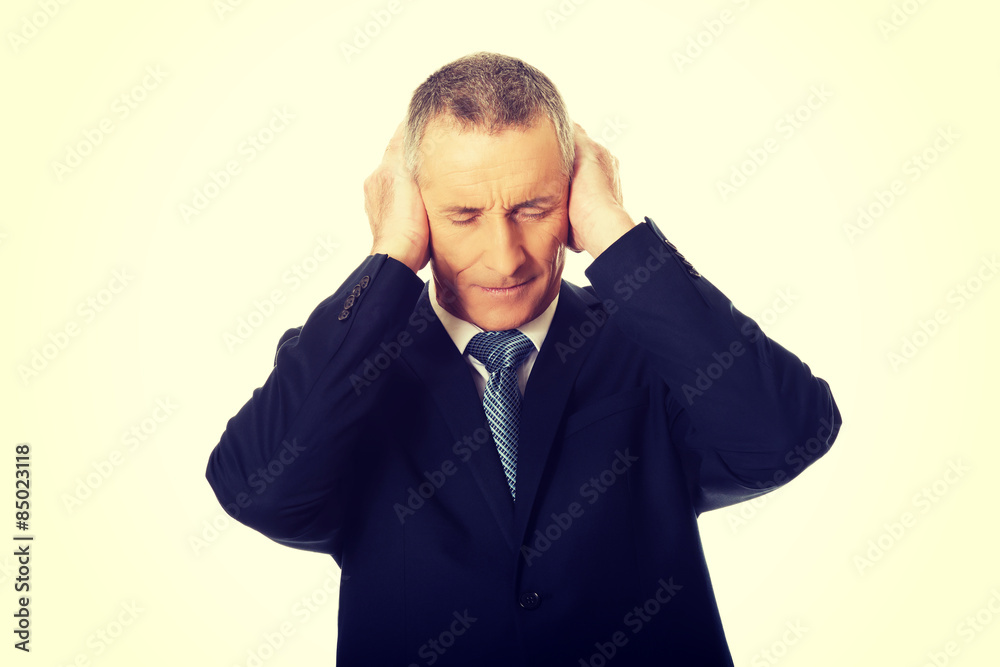 Tired businessman covering ears with hands Tired businessman covering ears with hands