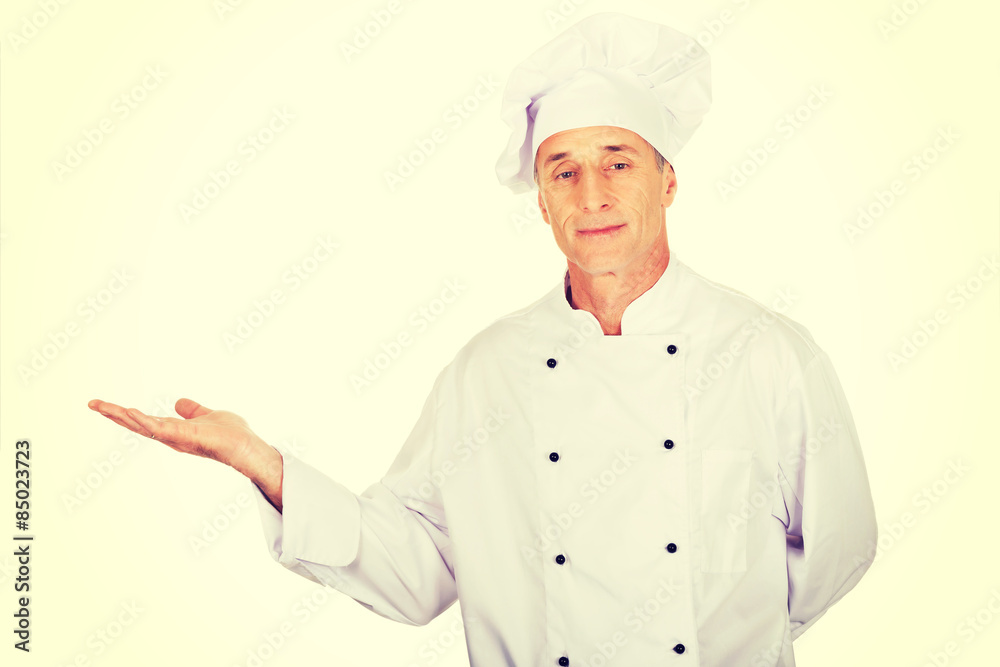 Mature chef showing copyspace on the left Mature chef showing copyspace on the left