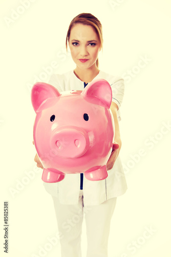 Young female doctor holding a piggybank. photo