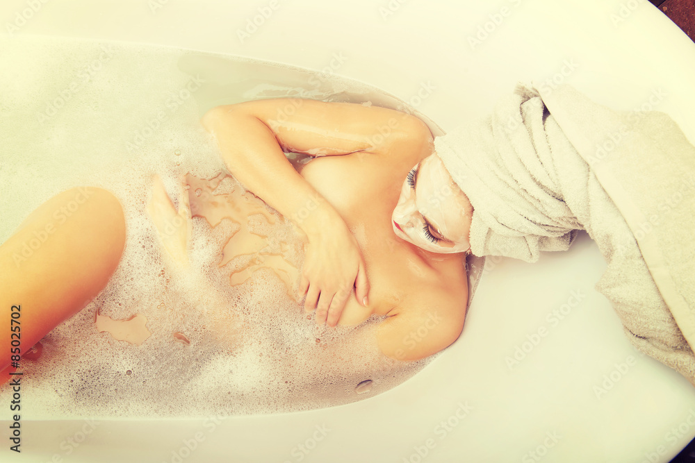 Woman relaxing in bathtub with face mask. Woman relaxing in bathtub with face mask.