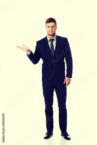 Handsome businessman holding copyspace on palm.