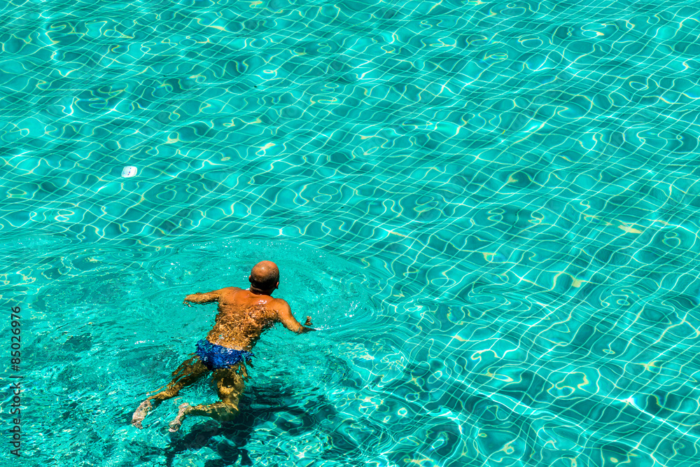 Naklejka Relaxing in swimming pool./ Man swimming in the crystal-clear pool.
