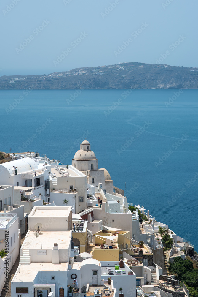 Small greek church building in Fira, Santorini, with a view of the caldera in the distance