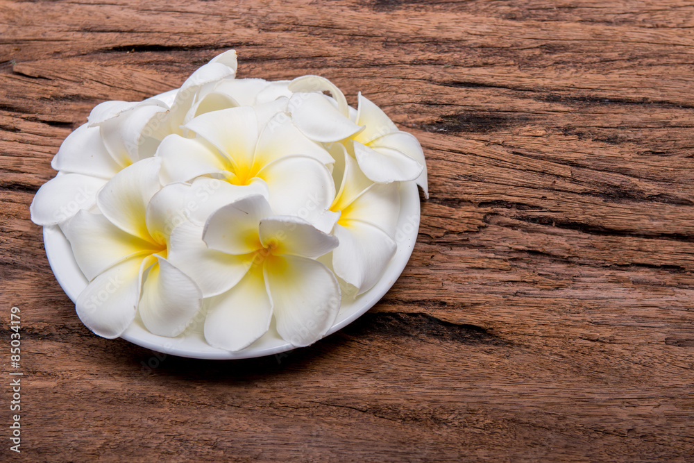 Naklejka premium Plumeria flowers on plate on wooden