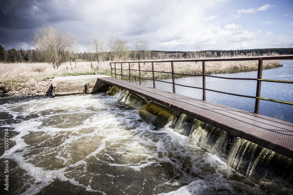 Old metal small water dam on a river.