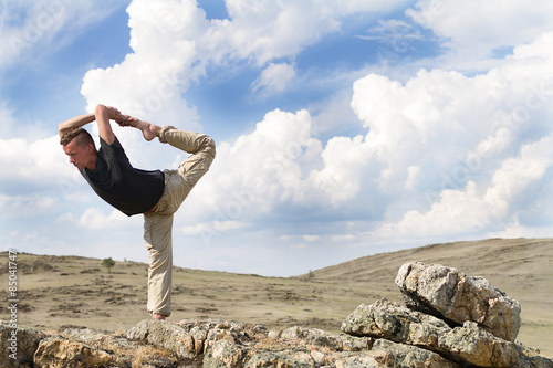 man practices yoga on the nature