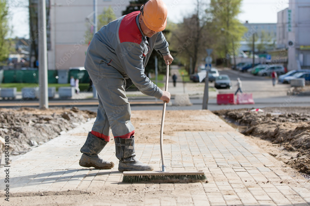 Construction worker grouting dry sand with brush into paver joints Stock Photo Adobe Stock