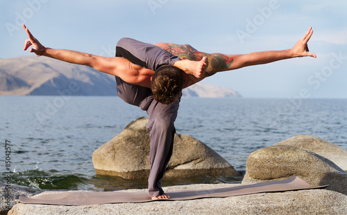 man practices yoga on the nature