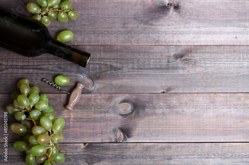 Bottle of white wine, grape and corkscrew on wooden table